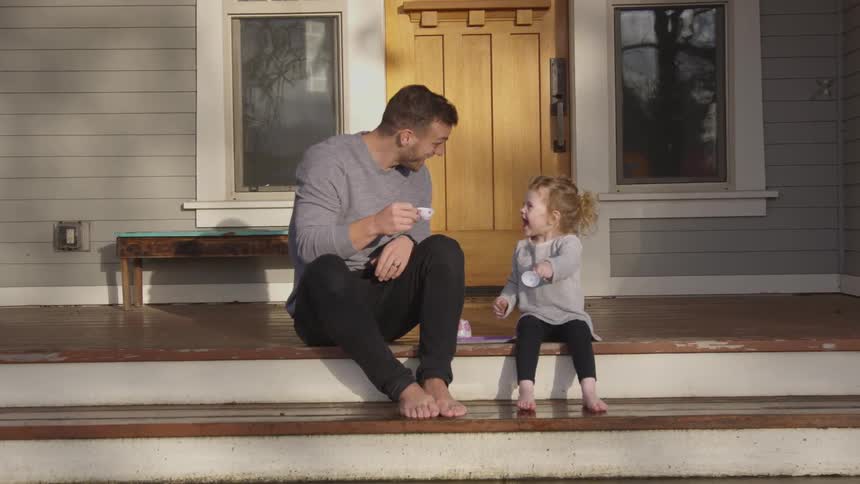 A man and a small female child sitting on the front step of a house