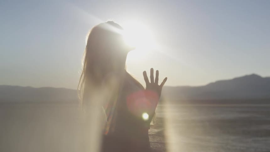 A woman stands in a sunny desert
