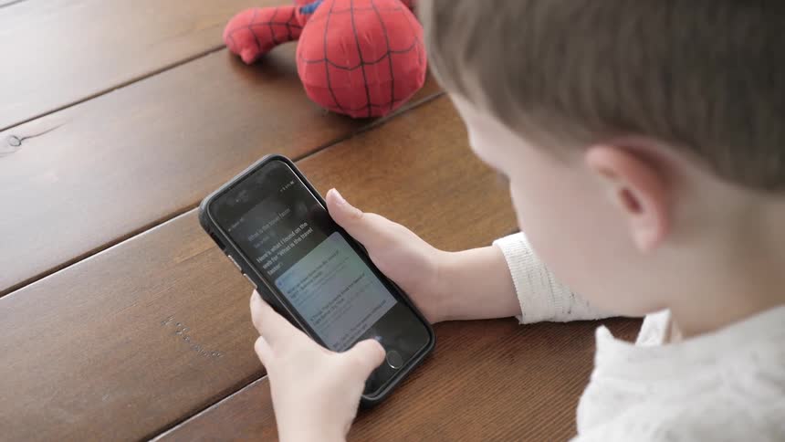 A young child swipes through a cell phone