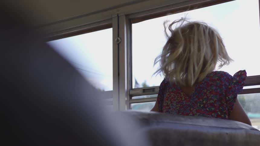 A little girl sticking her head out a bus window