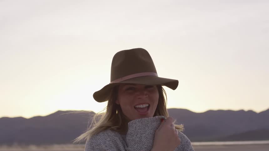 A woman laughs and covers her face with her sweater