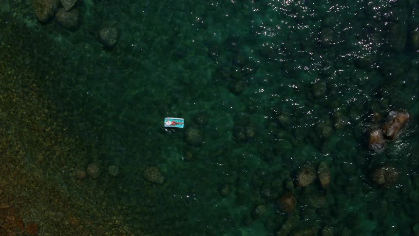 Woman Sunbathing On Raft In Water