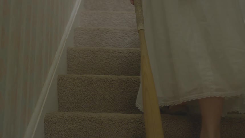 Woman carrying a baseball bat walks up the stairs