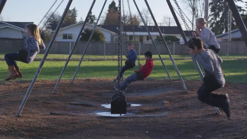 Six kids playing on a swing set in a park