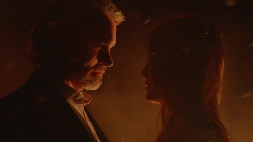 Two lovers approach each other while a fire burns all around them
