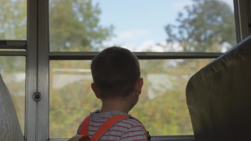 A boy sitting on a bus looking out of the window
