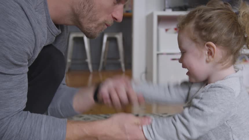 A man shakes the arms of a toddler playing a game