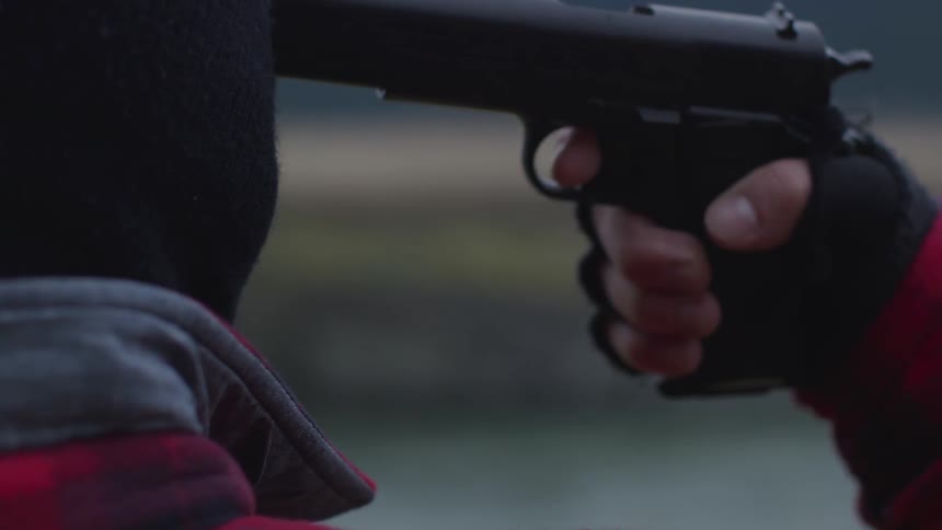 Someone puts a gun to a person wearing a balaclavas head