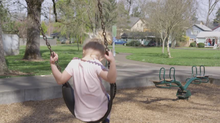Two children swing at the playground
