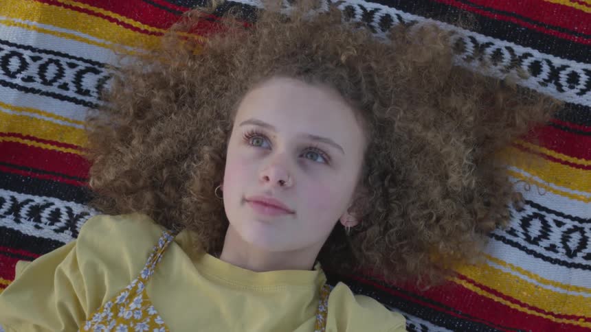 Woman laying on a vibrant blanket on the ground