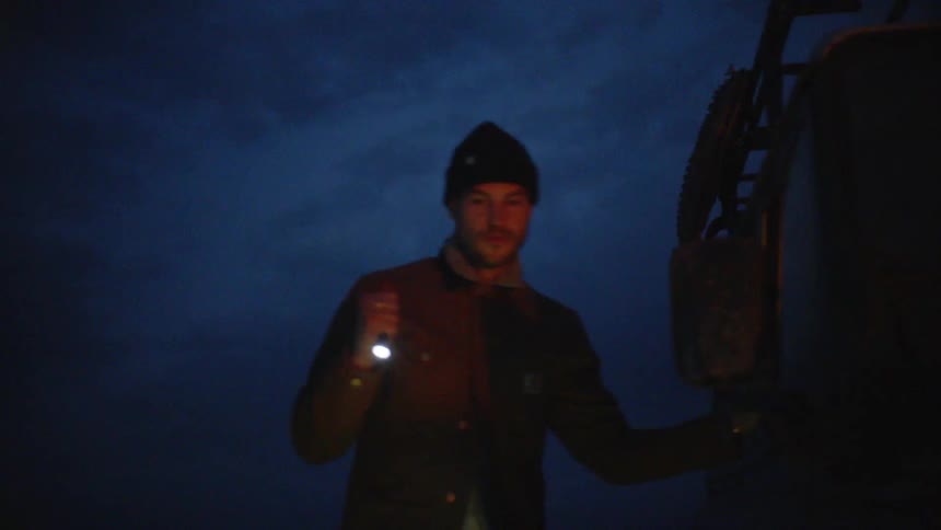 A man is getting out of a car while holding a flashlight