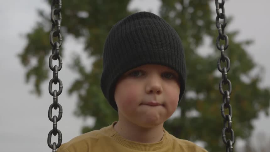 A small child wearing a beanie on a swing