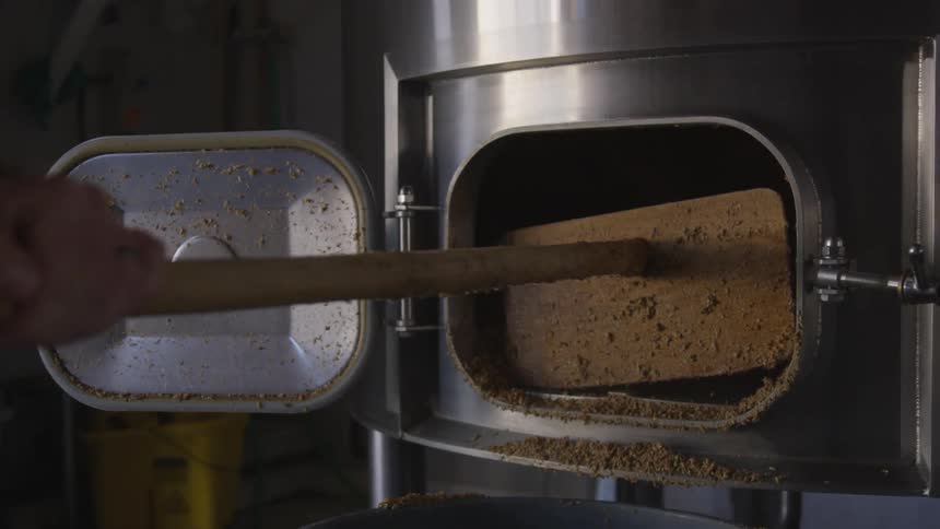 Man pulling some type of granules out of a large vat