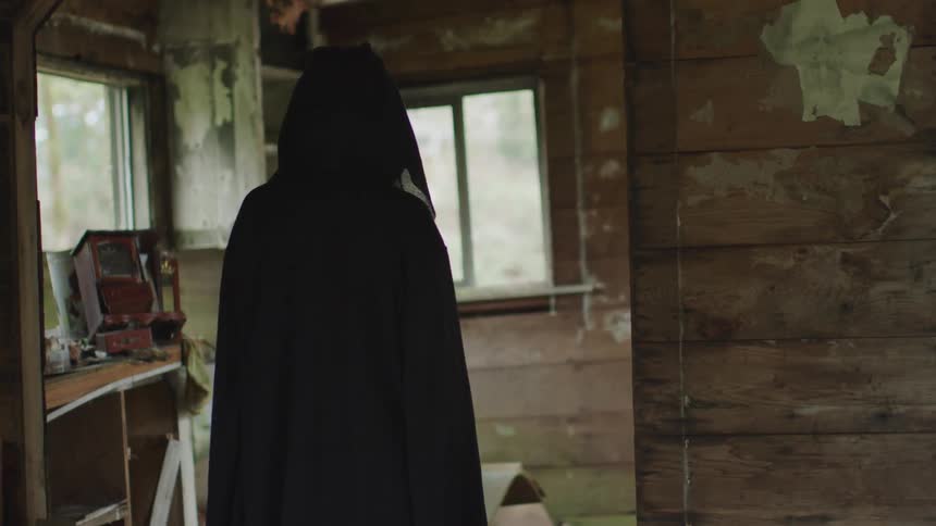 A person in a black robe is standing in the home