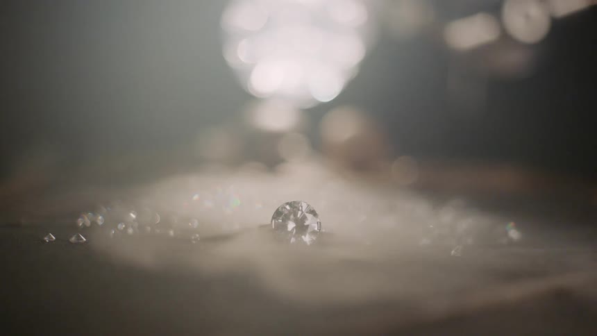 A diamond ring sitting on a table of sand