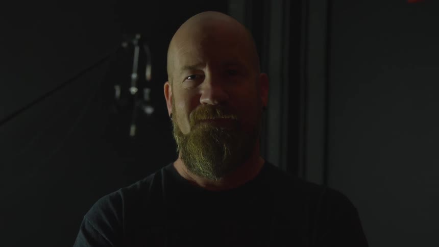 Bald man with beard smiles at camera