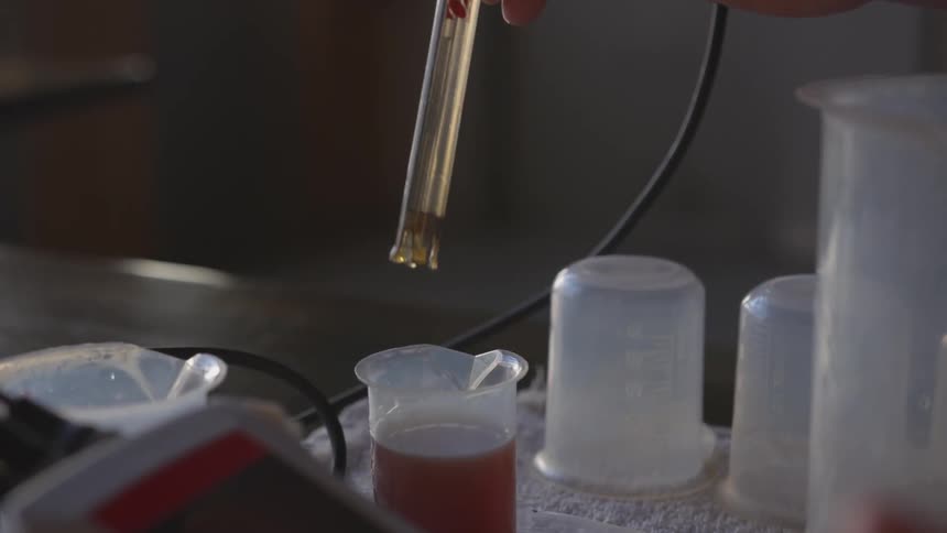 Person drops substance into a plastic beaker