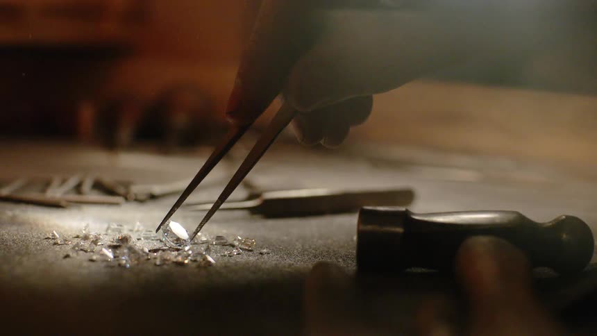 Someone is picking up diamonds with a tweezer