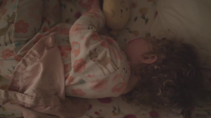 Young curly head girl sleeping in her bed with her doll