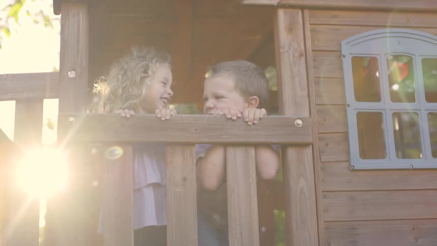 Two blond kids playing in a little playhouse