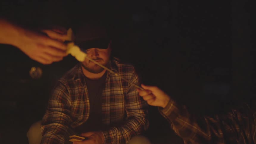 People cook over a campfire at night