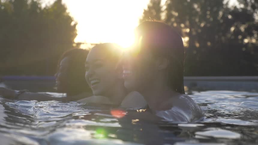 Three woman laugh while in swimming pool
