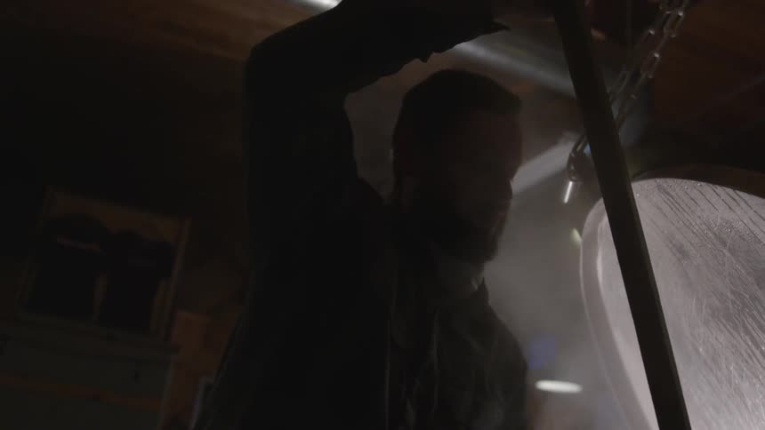 A man is stirring a beer vat in a brewery