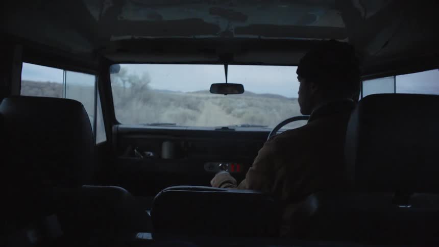 A man driving a van down a dirt road