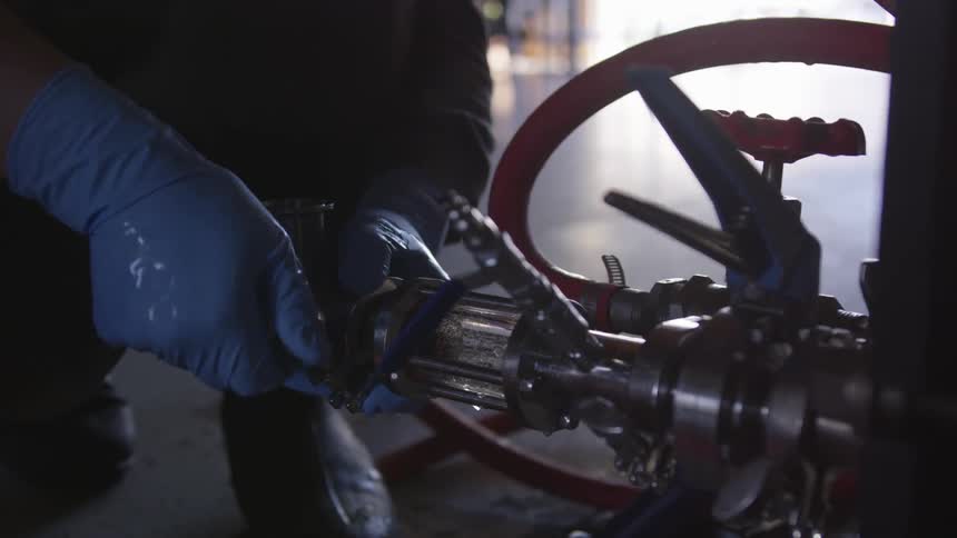 A person is wearing gloves and turning an object
