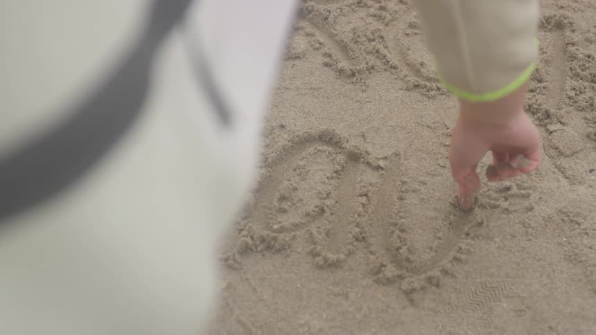 A boy writing on sand with his fingers