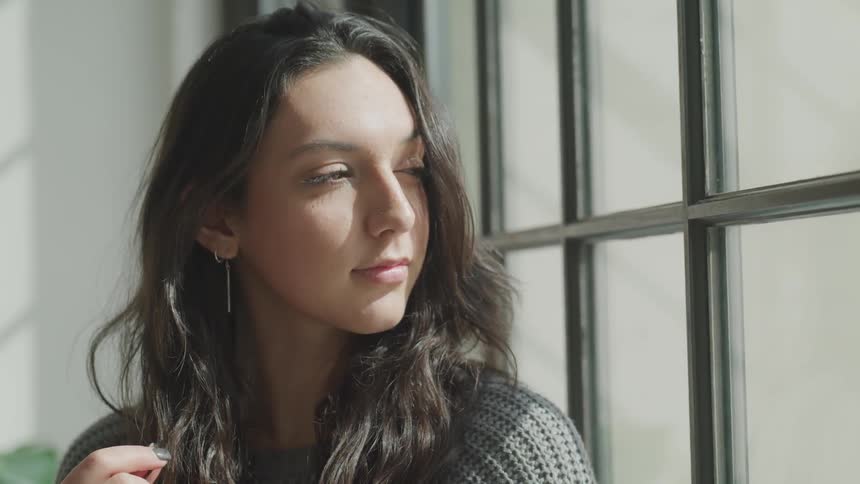 Woman in a sweater staring out a window
