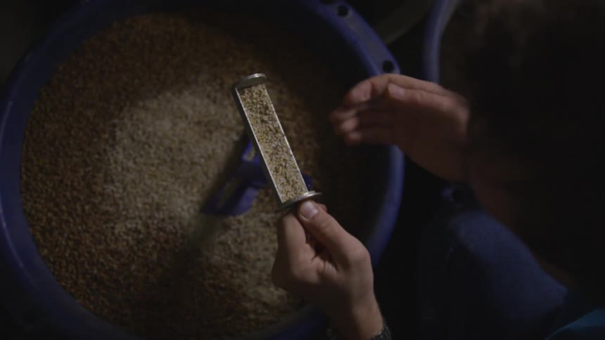 Man pulling some type of granules out of a large vat and into a rubber container