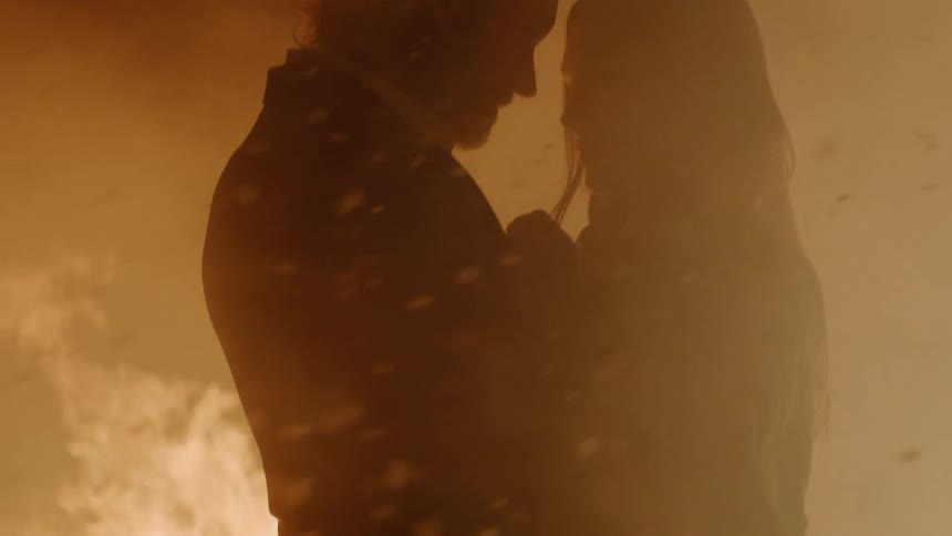 A man and woman are holding each other by a fire