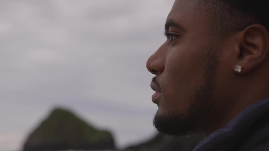 A man stares outside under overcast skies