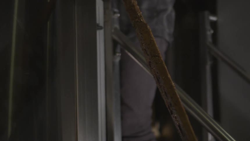 A man stirs a large vat in a brewery
