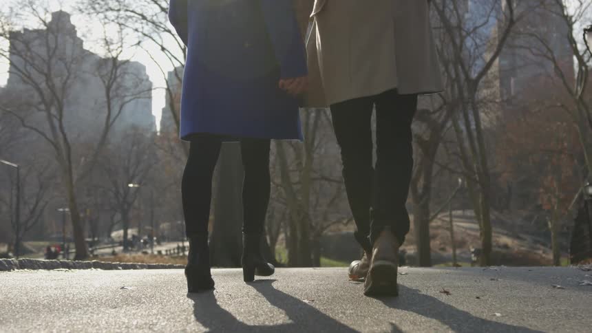 Two people walk together out in the city park