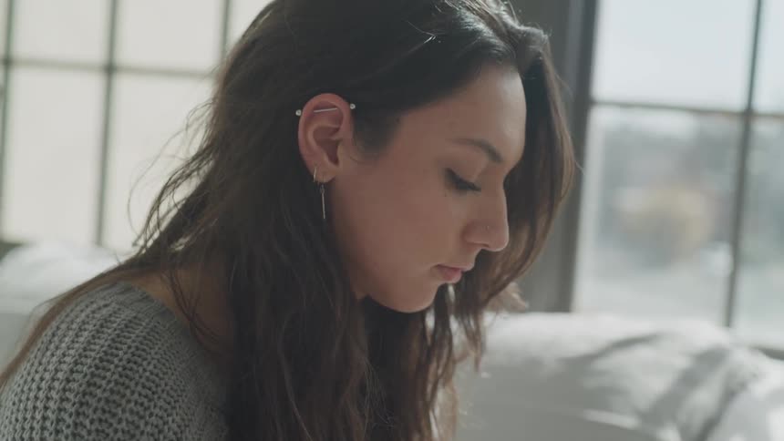 A woman brushes her hair back behind her ear