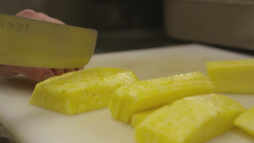 A person is cutting pineapples on a table