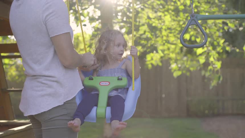 A woman straps a toddler into a swing