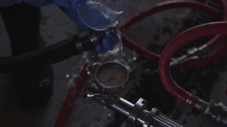 A person using a cup to pour water down a hose