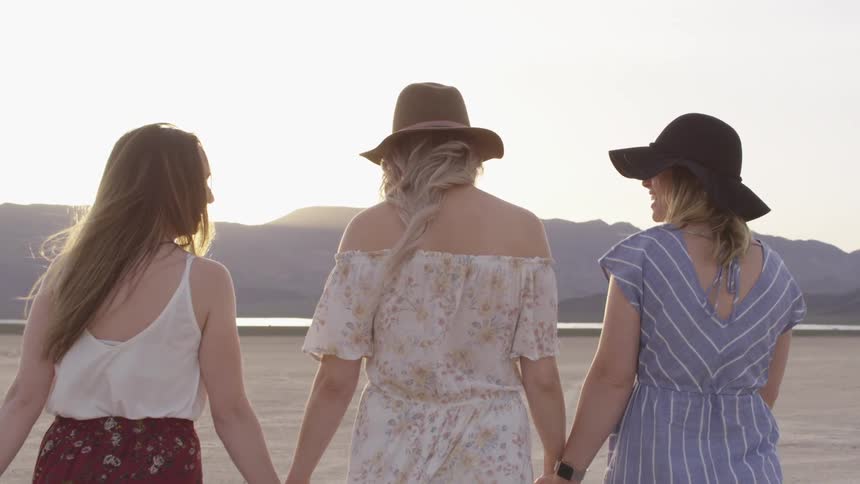Three women walking together in a dried lake bed