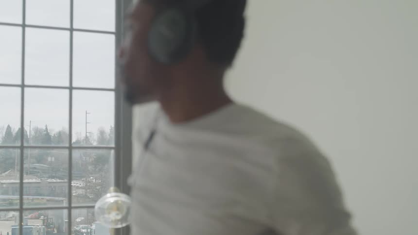 A man listening to headphones looks out the window
