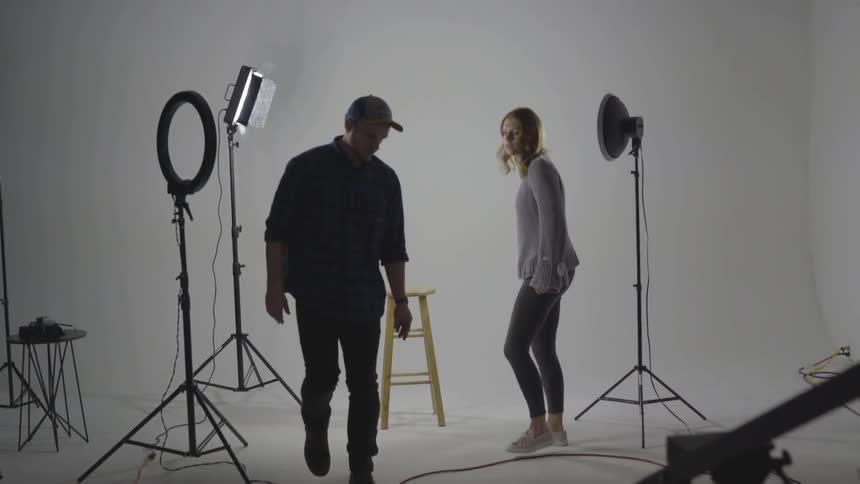 A man setting up a stool for a woman to sit down on