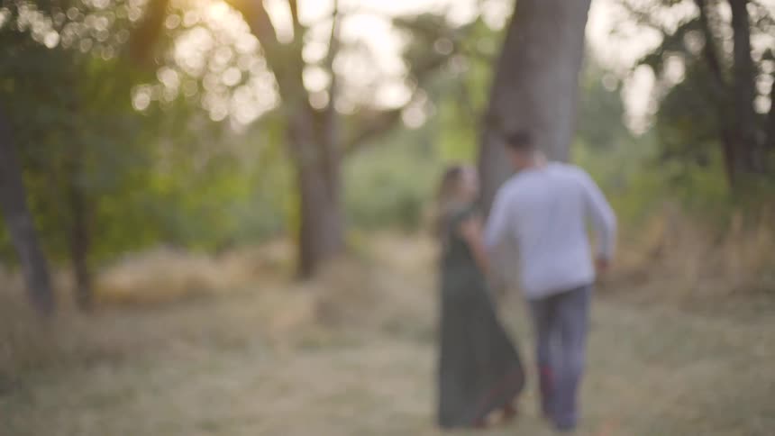 A man and woman walk through the woods