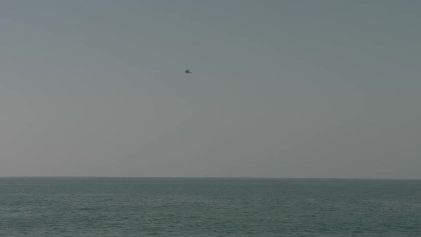 A helicopter flies over an ocean