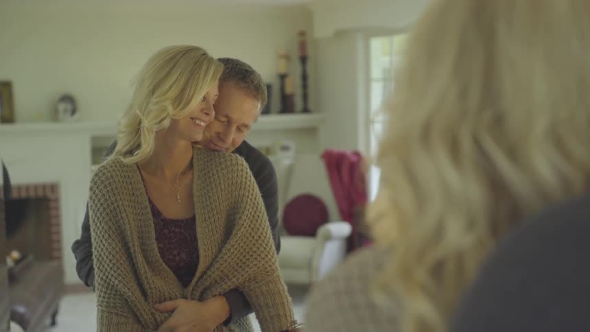A man and woman stand in front of mirror hugging