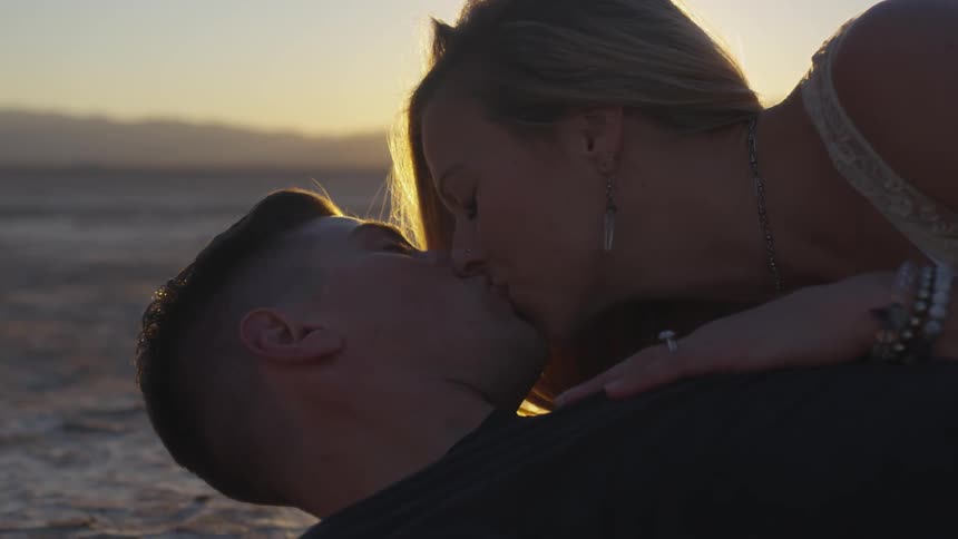 Man and woman lying on a beach kissing