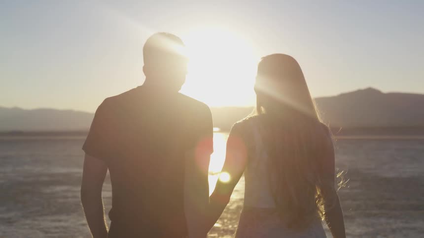 A man and woman hold hands by the ocean