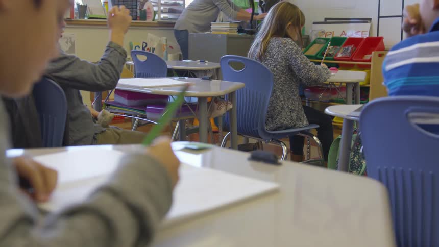 Children sits writing at their desks in class