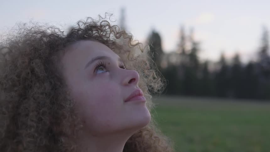 A woman looks around at the cloudy sky